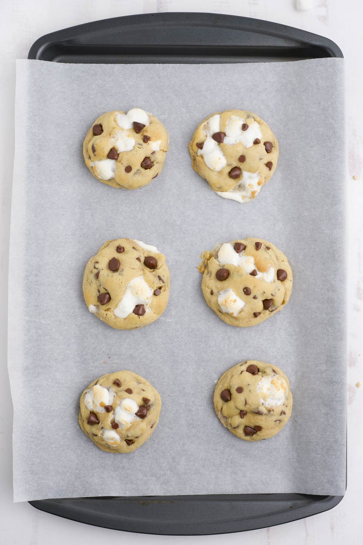 Baked chocolate chip marshmallow cookies on a baking tray.
