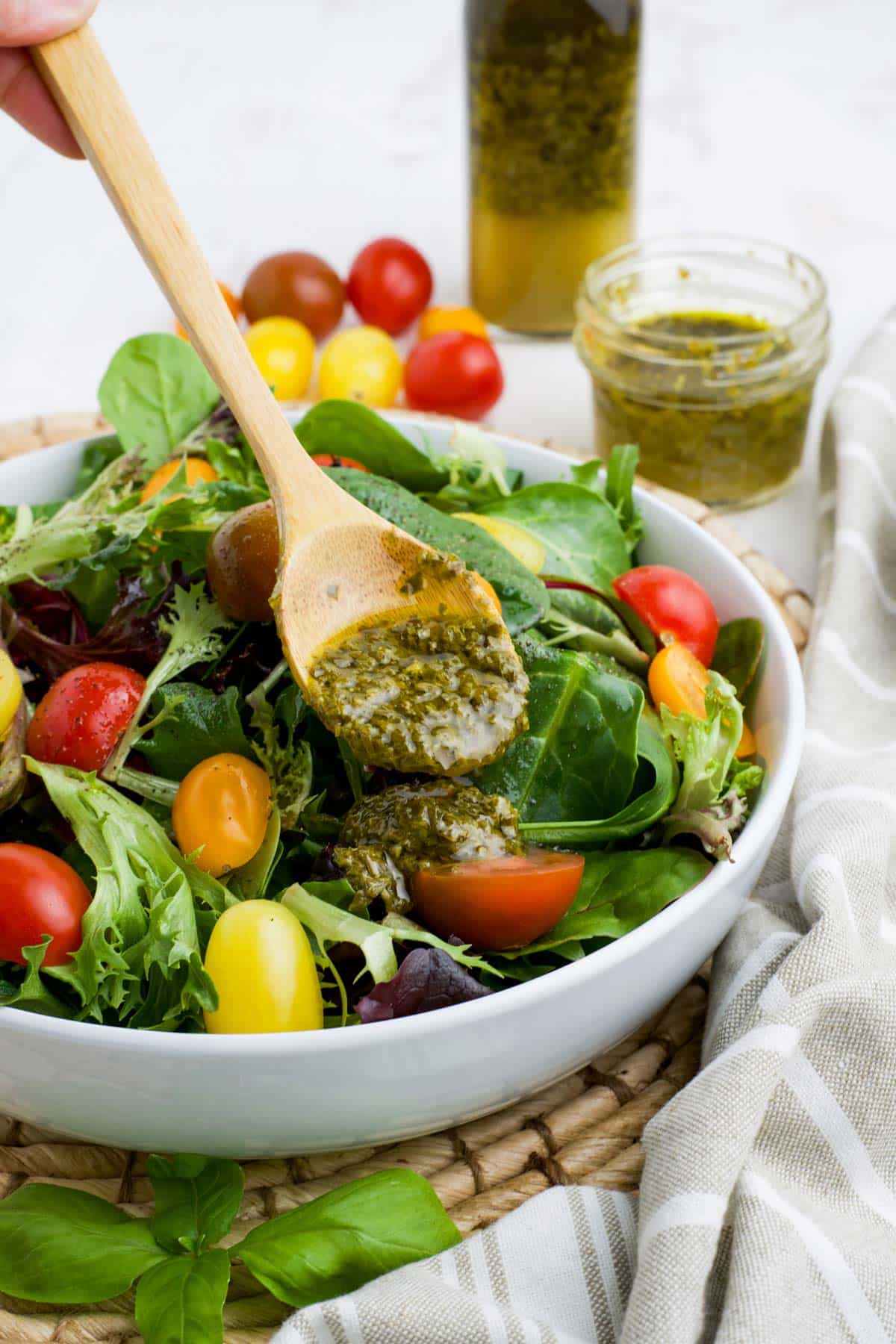 Salad with a spoonful of pesto salad dressing to pour over the top of the salad.