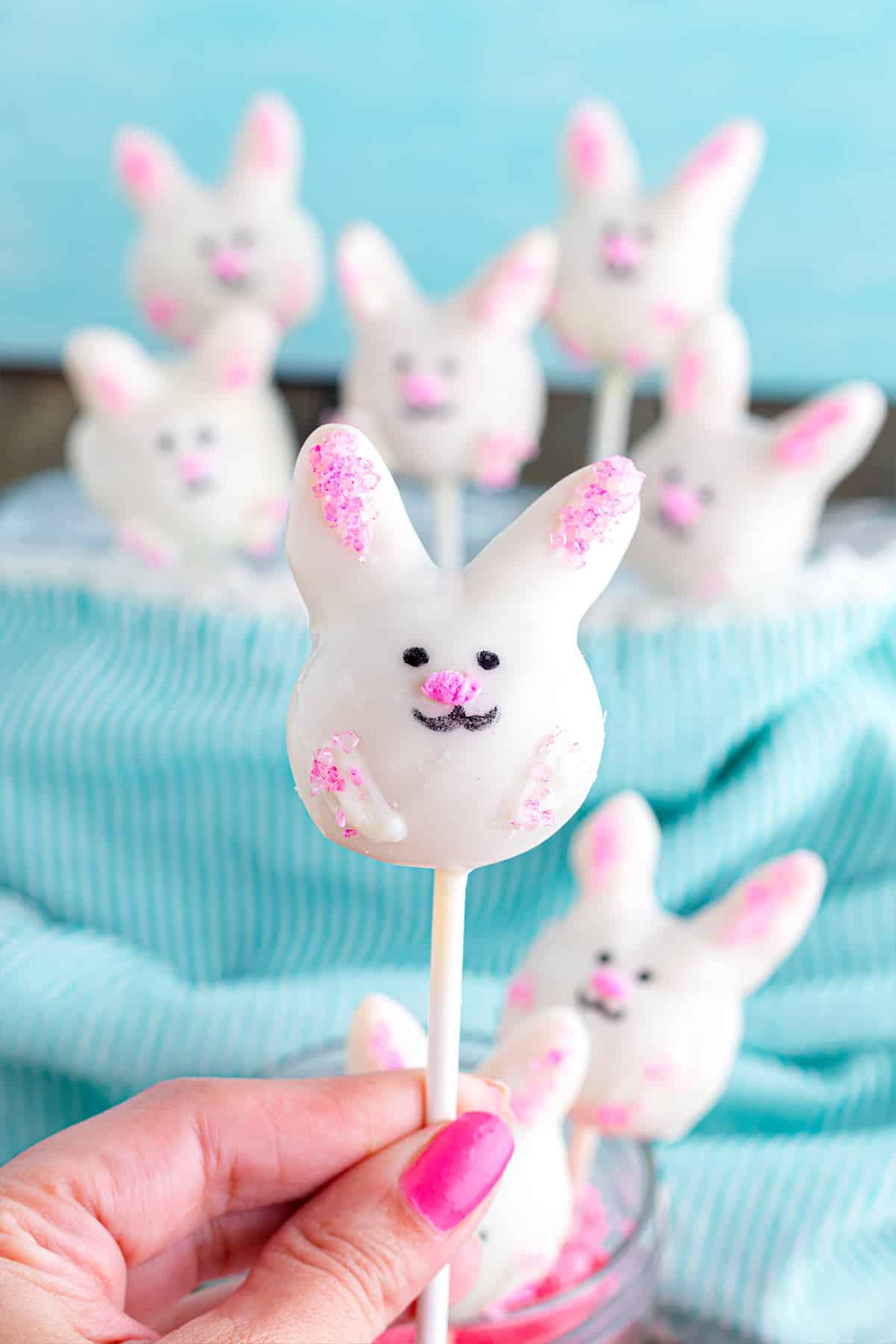 A hand holding up a single bunny cake pop to show what it looks like.