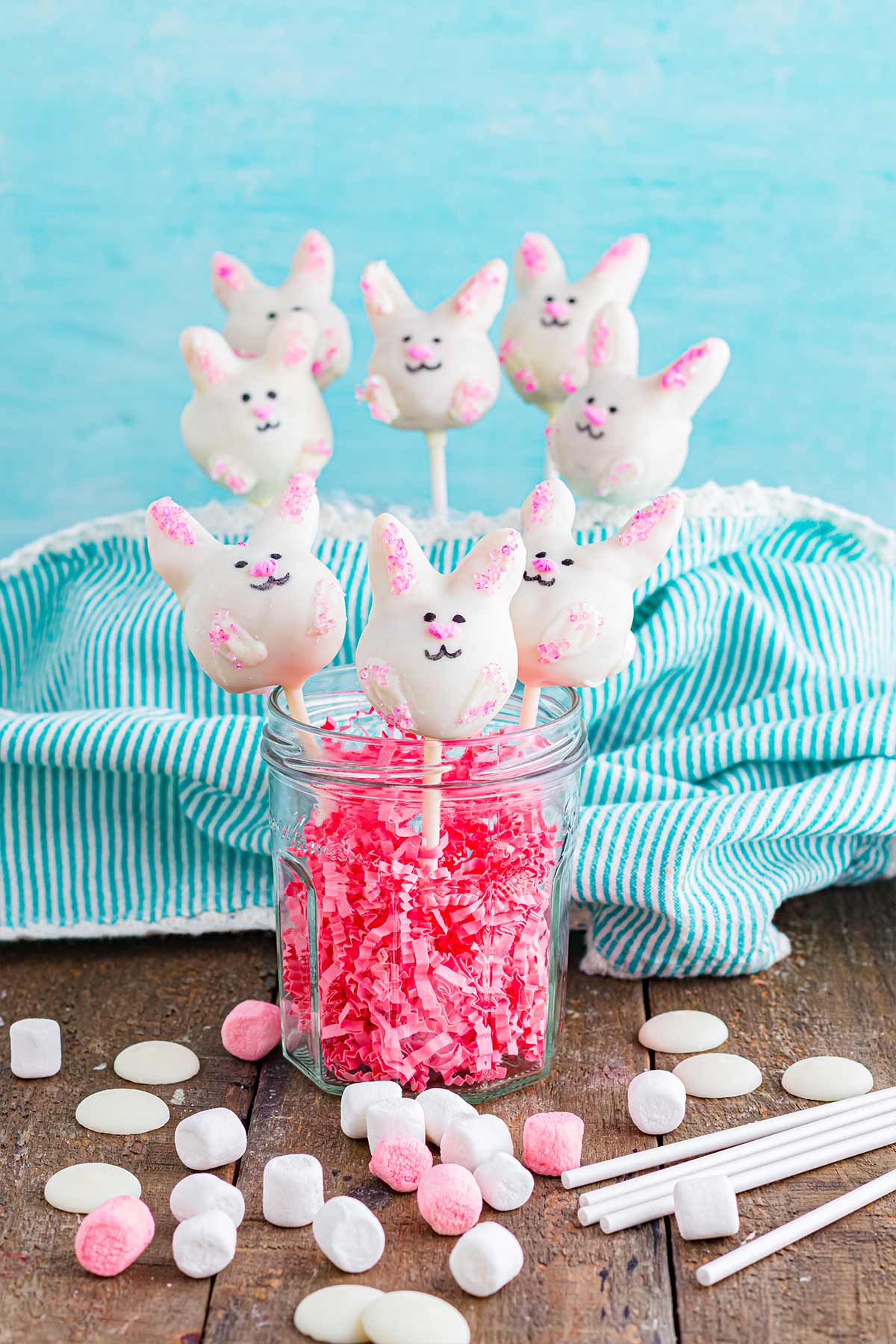 A jar with shredded pink paper and bunny cake pops inside.