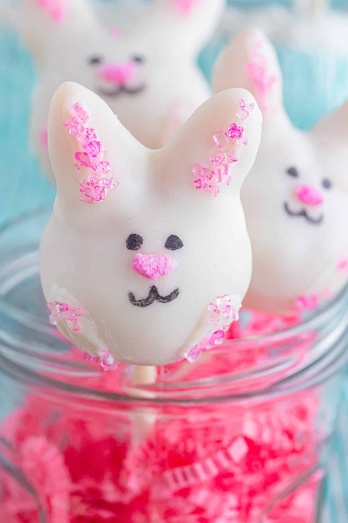 A close up of a Easter bunny cake pop in a glass jar.