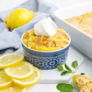 A bowl of lemon dump cake topped with whipped cream.