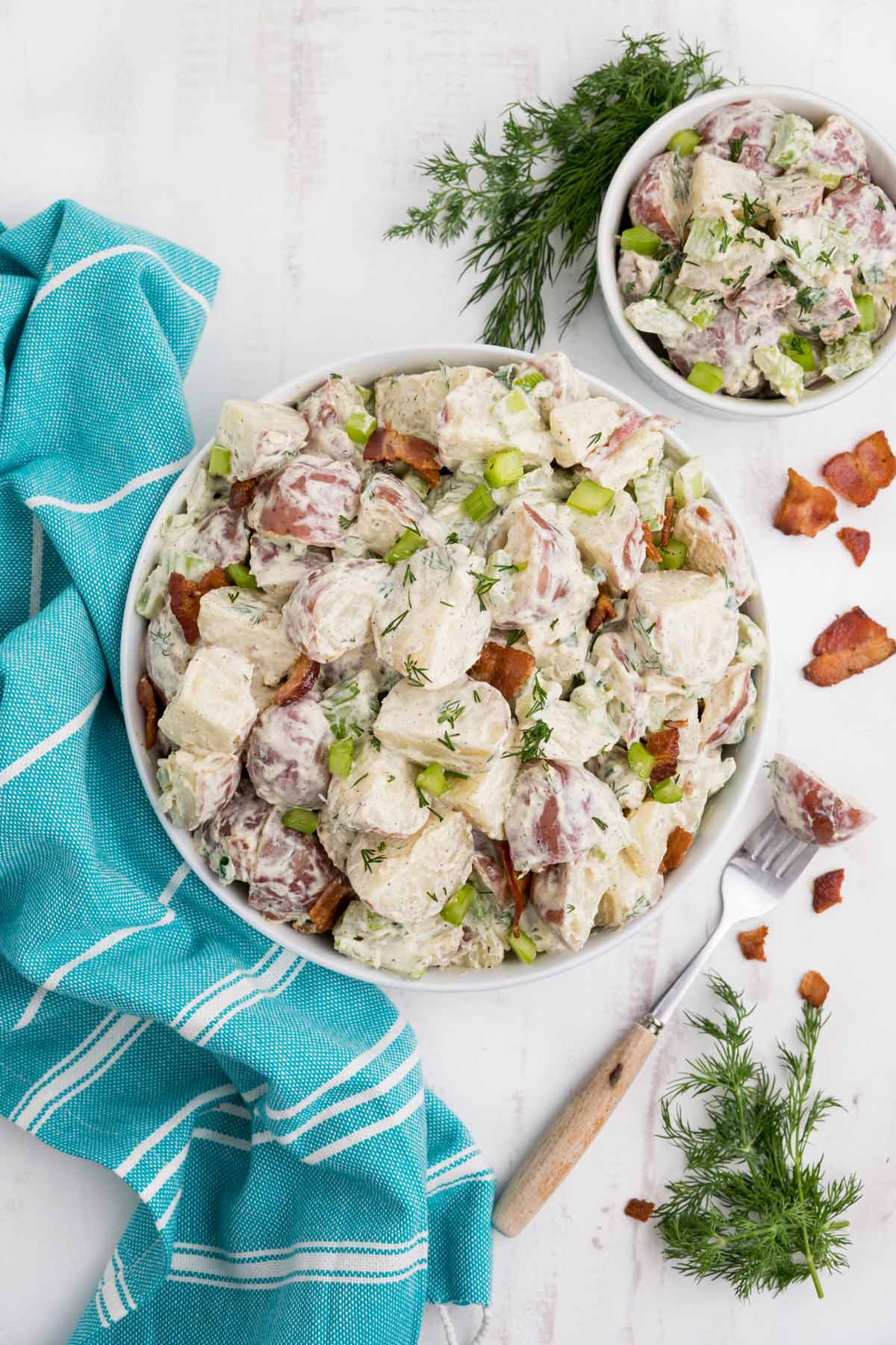 Bowl of red skin potato salad on the table with bacon pieces.