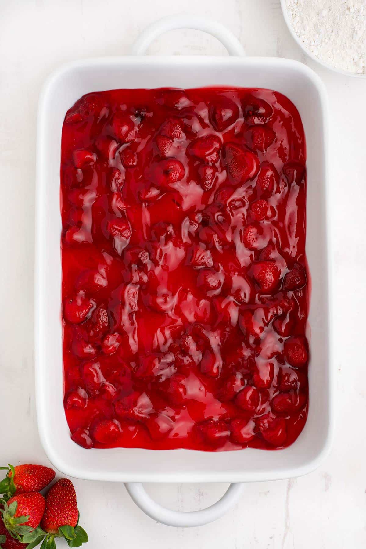Strawberry pie filling spread in the bottom of a baking dish.