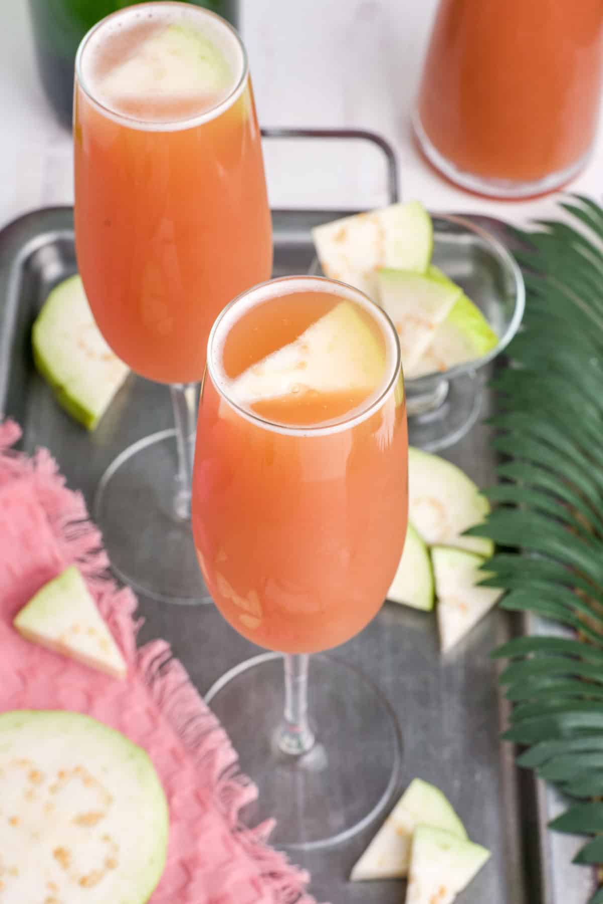 Guava mimosas on the table garnished with fresh guava.