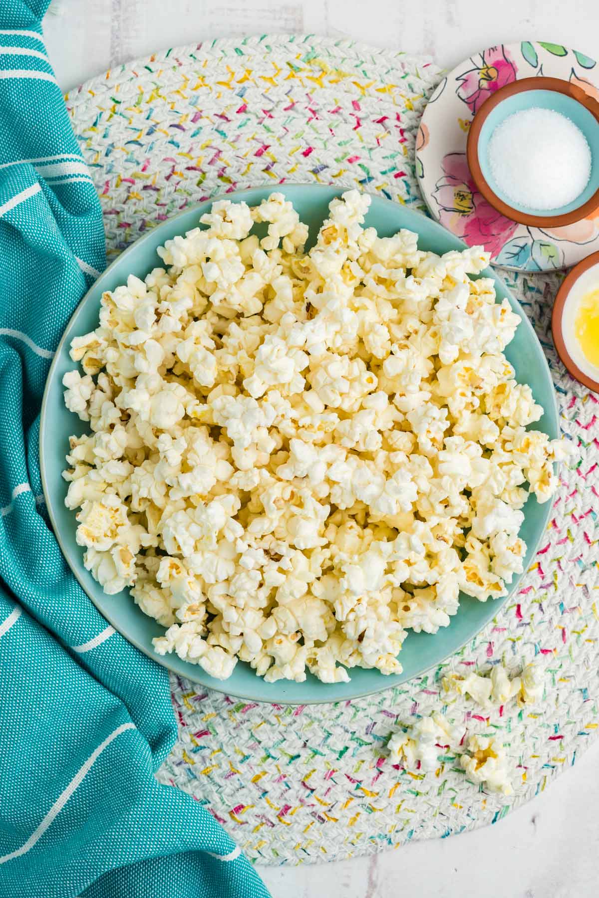 A bowl of air fryer popcorn on the table with salt and butter in little bowls on the side.
