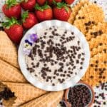 Easy cannoli dip in a bowl surrounded by strawberries and waffle crackers.