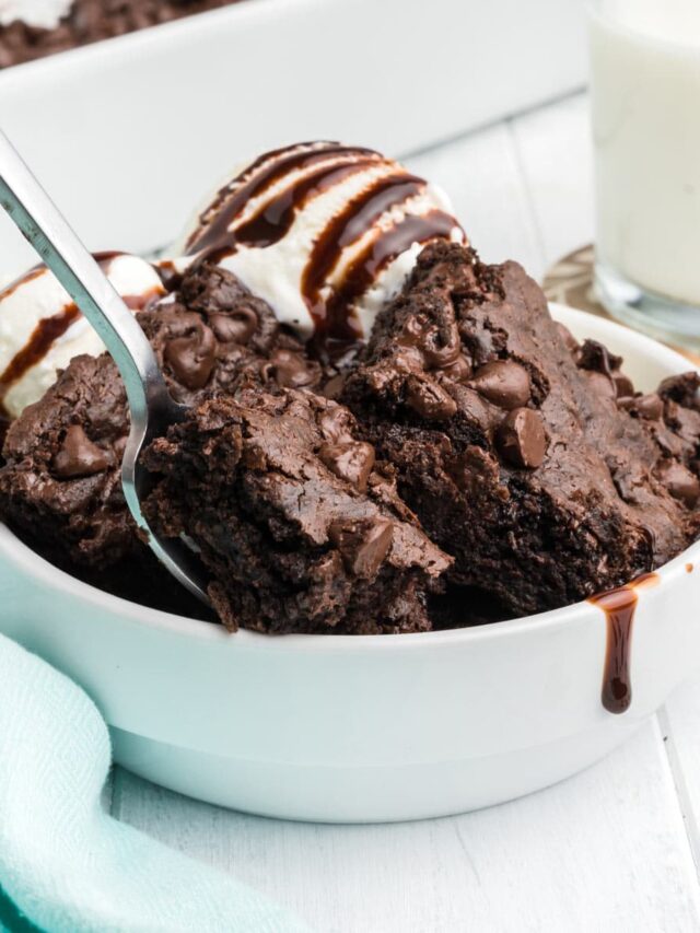 A bowl of chocolate dump cake with a scoop of ice cream and a spoon in the bowl.