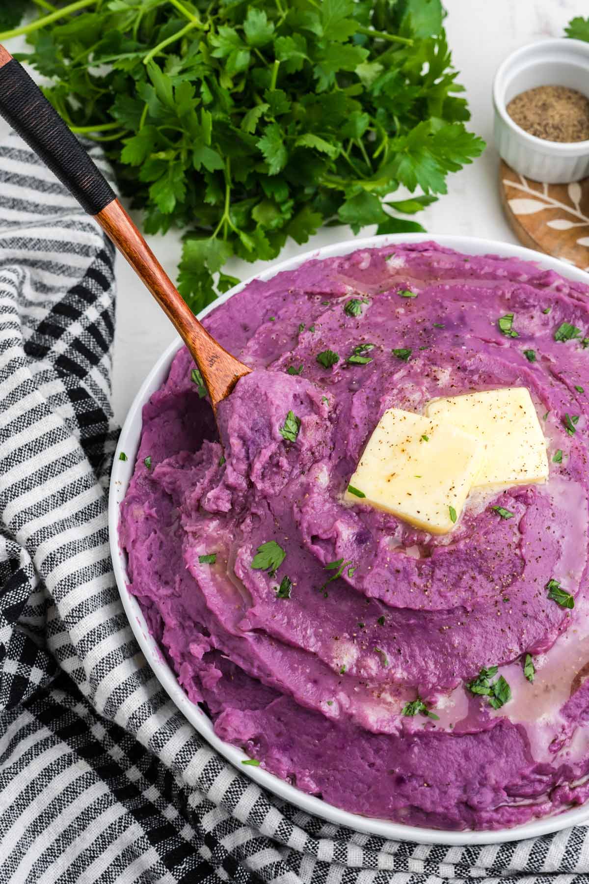 A bowl of mashed purple potatoes on the table with a spoon in the bowl.