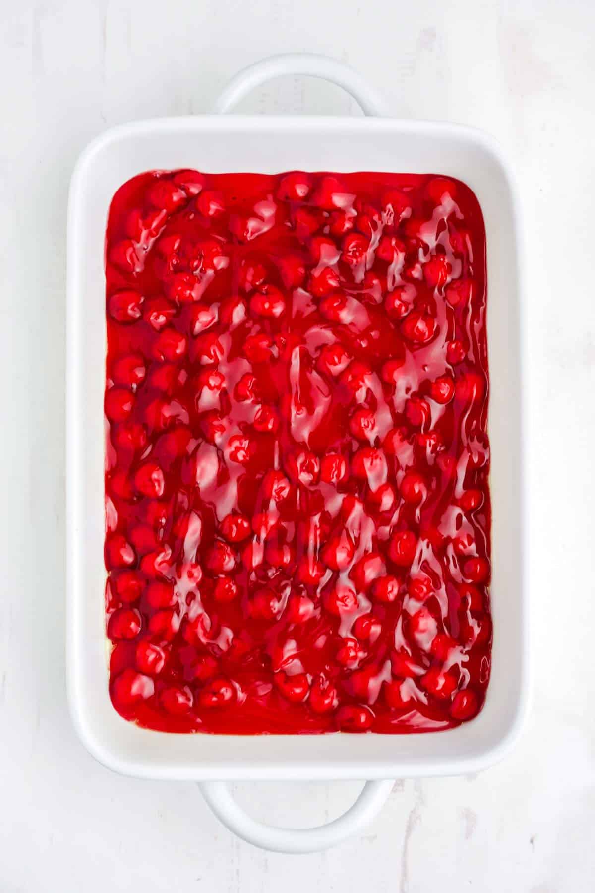 Cherry filling spread out in the bottom of the cooking dish.
