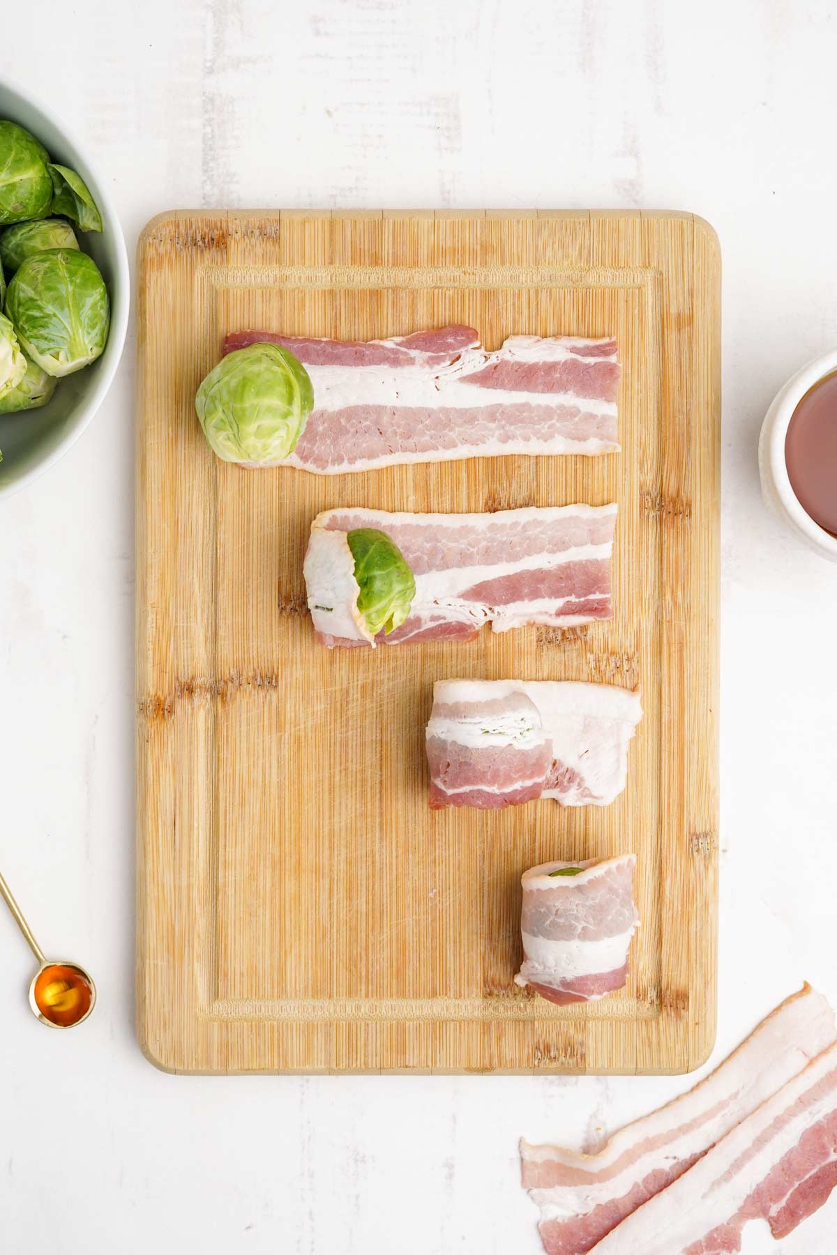 Brussel sprouts added to bacon strips and shown at various intervals of wrapping.