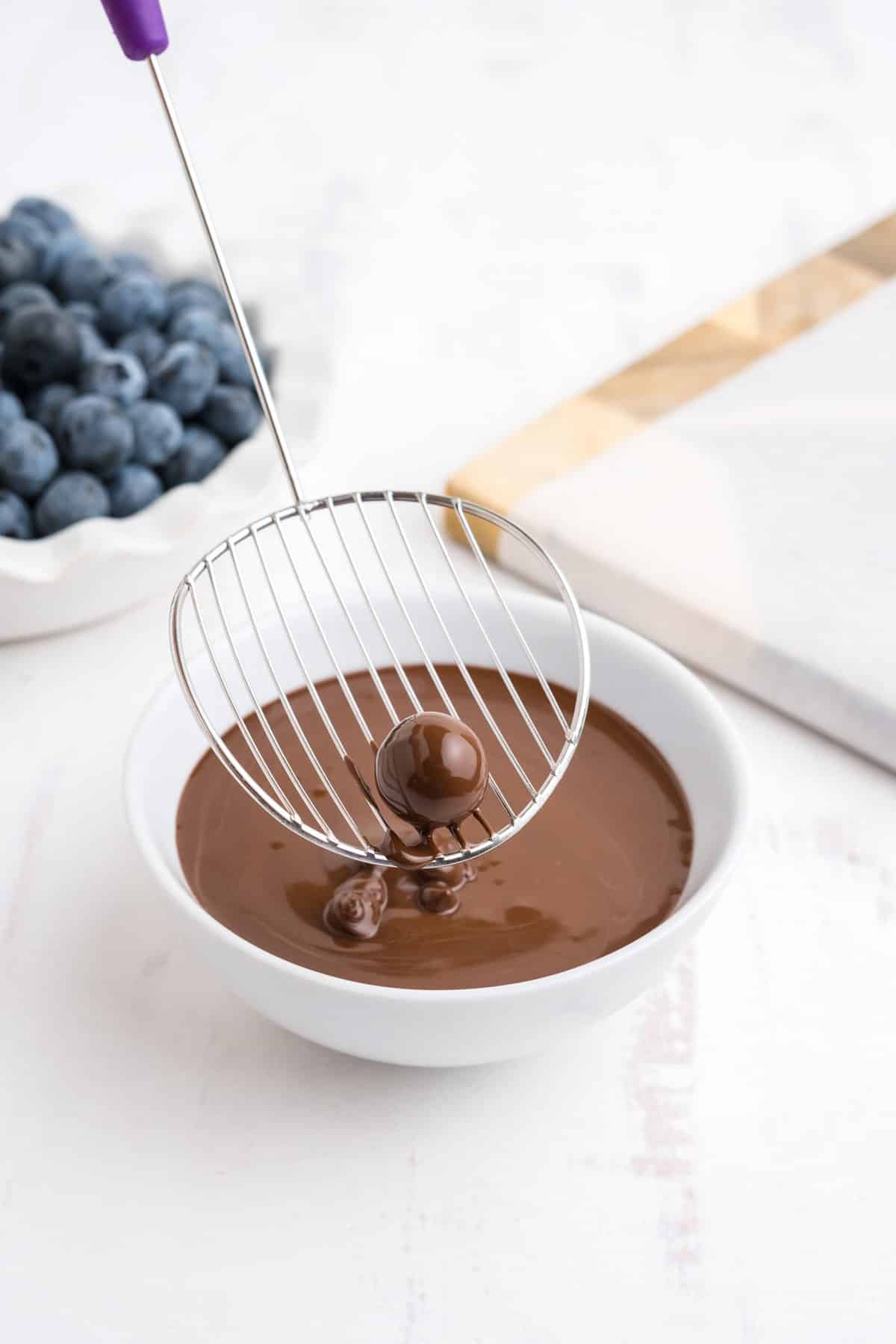 Dipping a blueberry in the chocolate sauce.