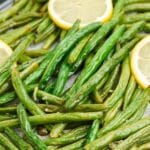 Close up of roasted green beans garnished with lemon slices.