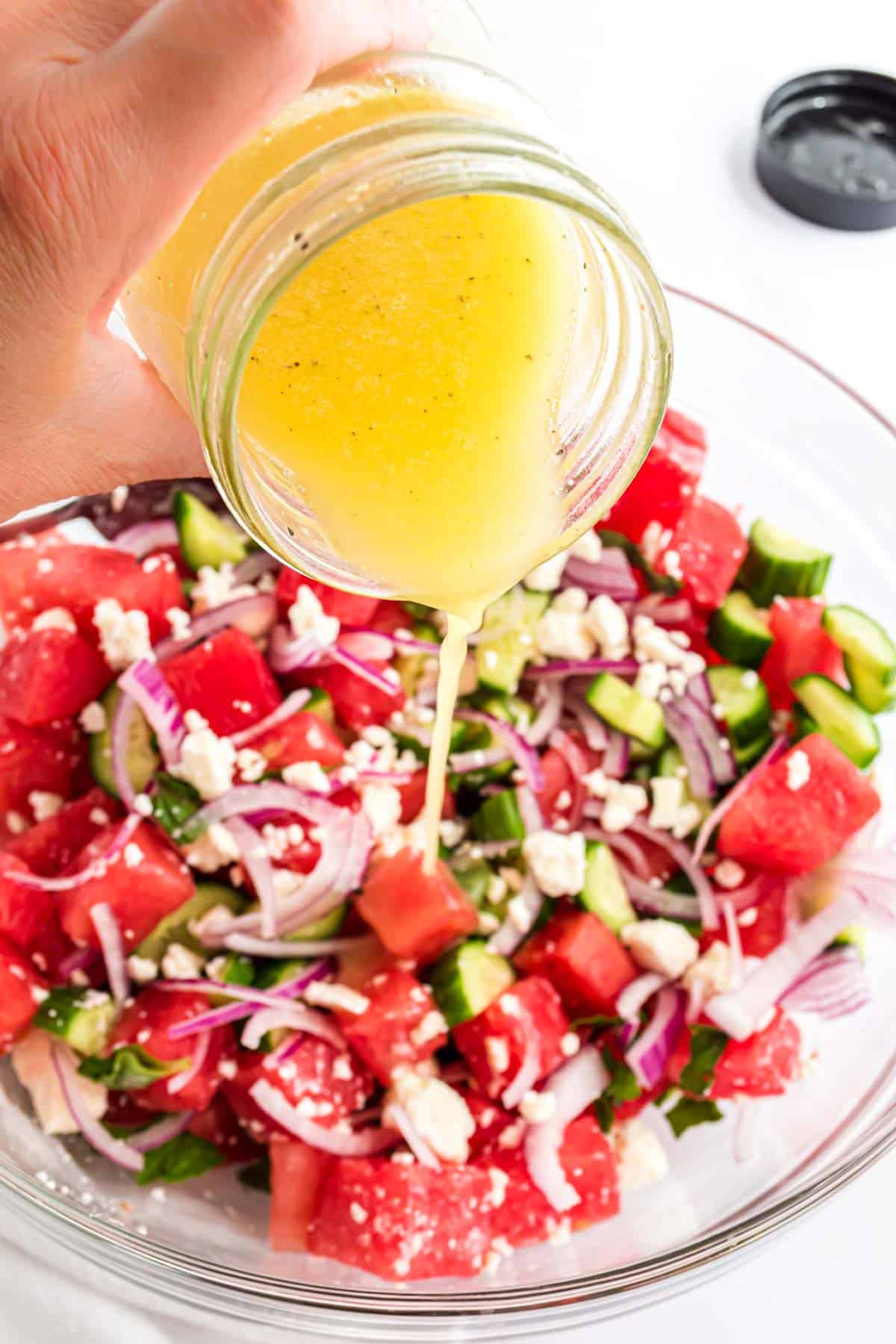 Adding the dressing to the bowl of watermelon salad.