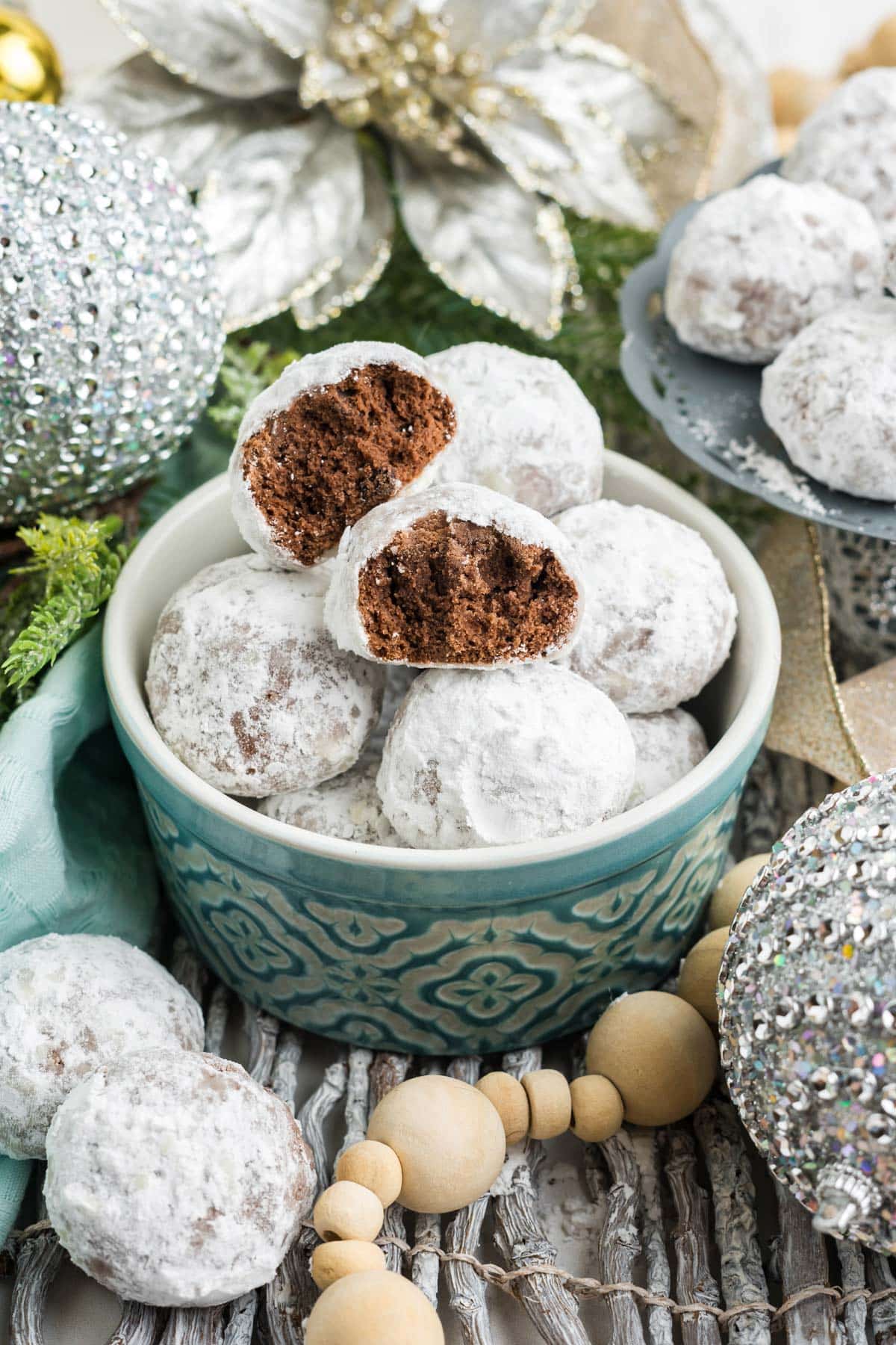 A bowl of chocolate snowball cookies on the table with one split in half on the top to show the chocolate inside.