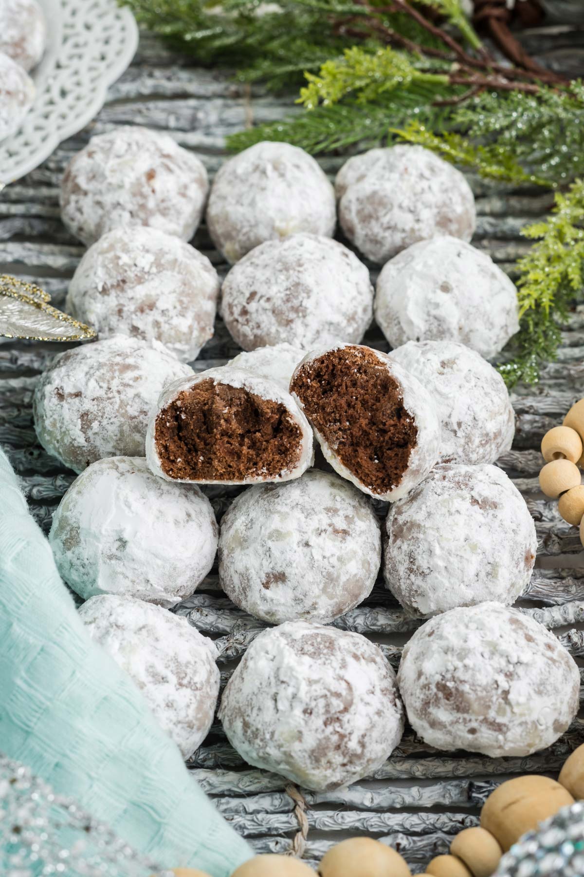 Chocolate snowball cookies lined up directly on the table with one broken in half on top.