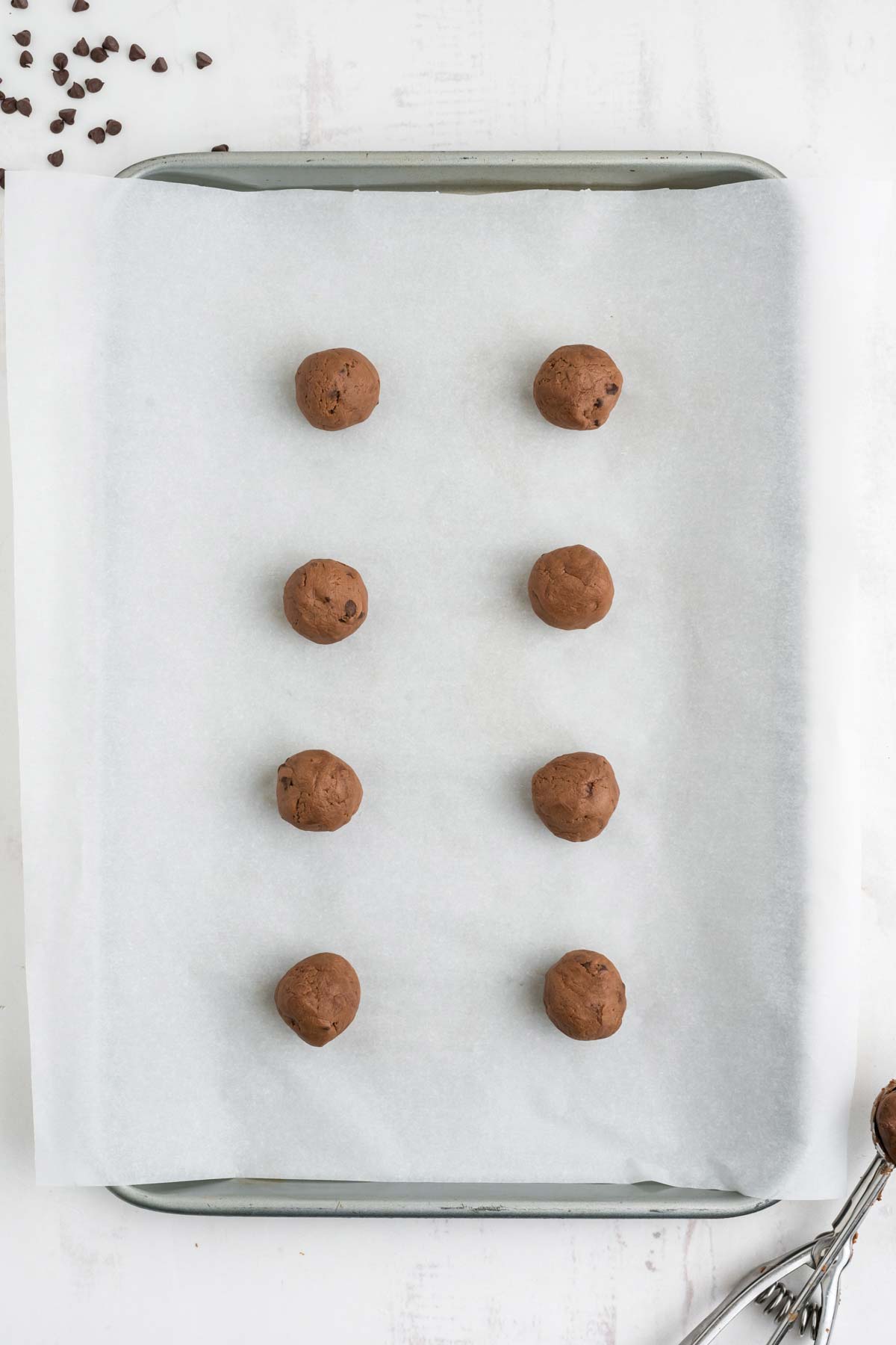 Chocolate cookie dough shaped into balls on a baking tray.
