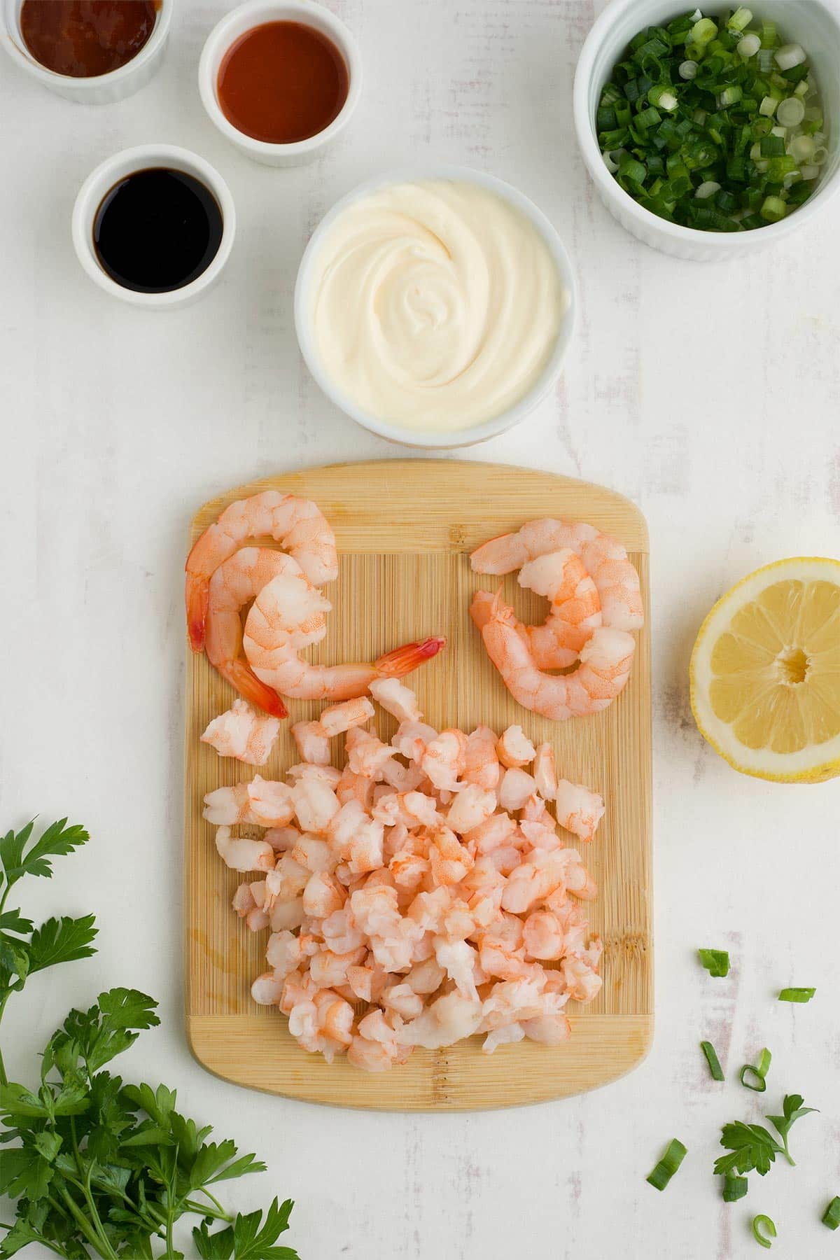 Shrimp cut up into little pieces on a small cutting board.