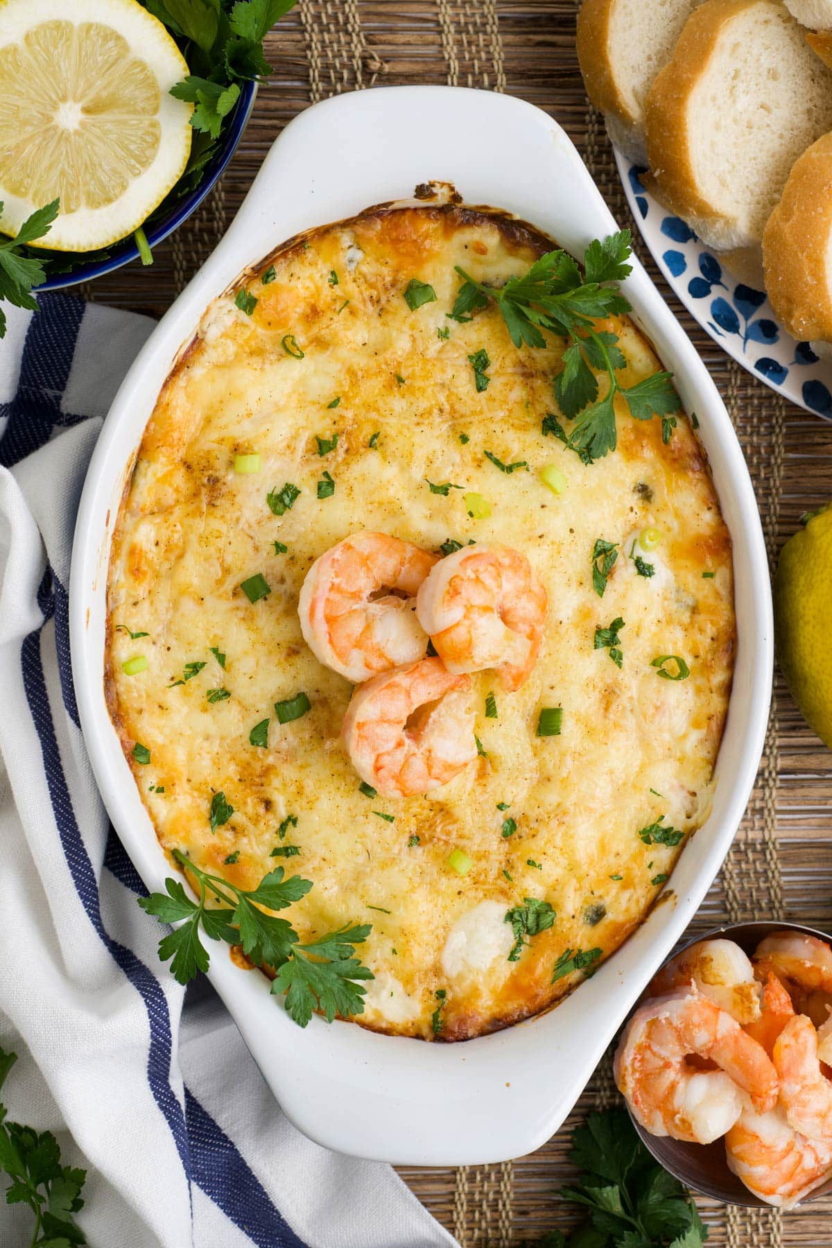 Overhead image of a dish of baked shrimp dip topped with parsley and three cooked shrimp for garnish.