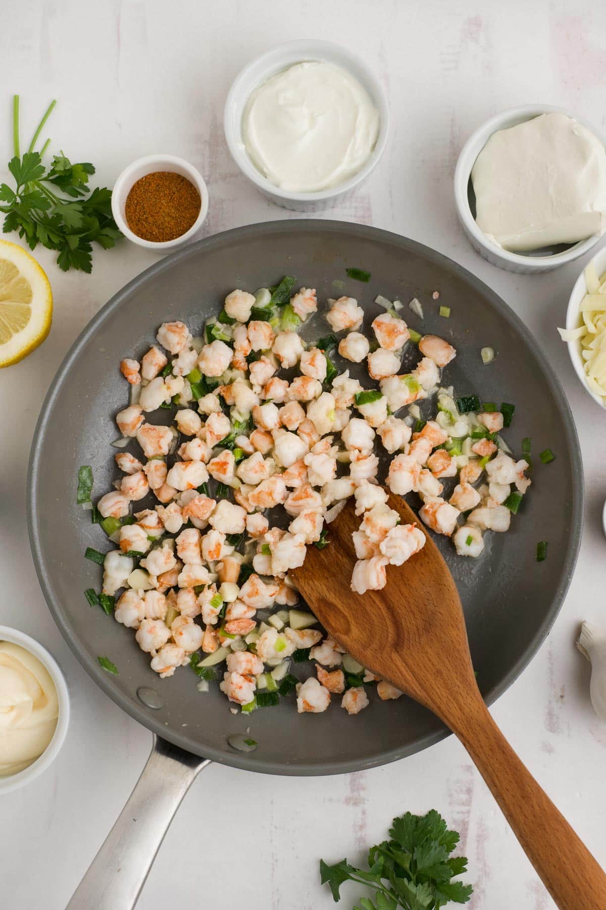 Cooking the shrimp in a skillet with a wooden spoon.