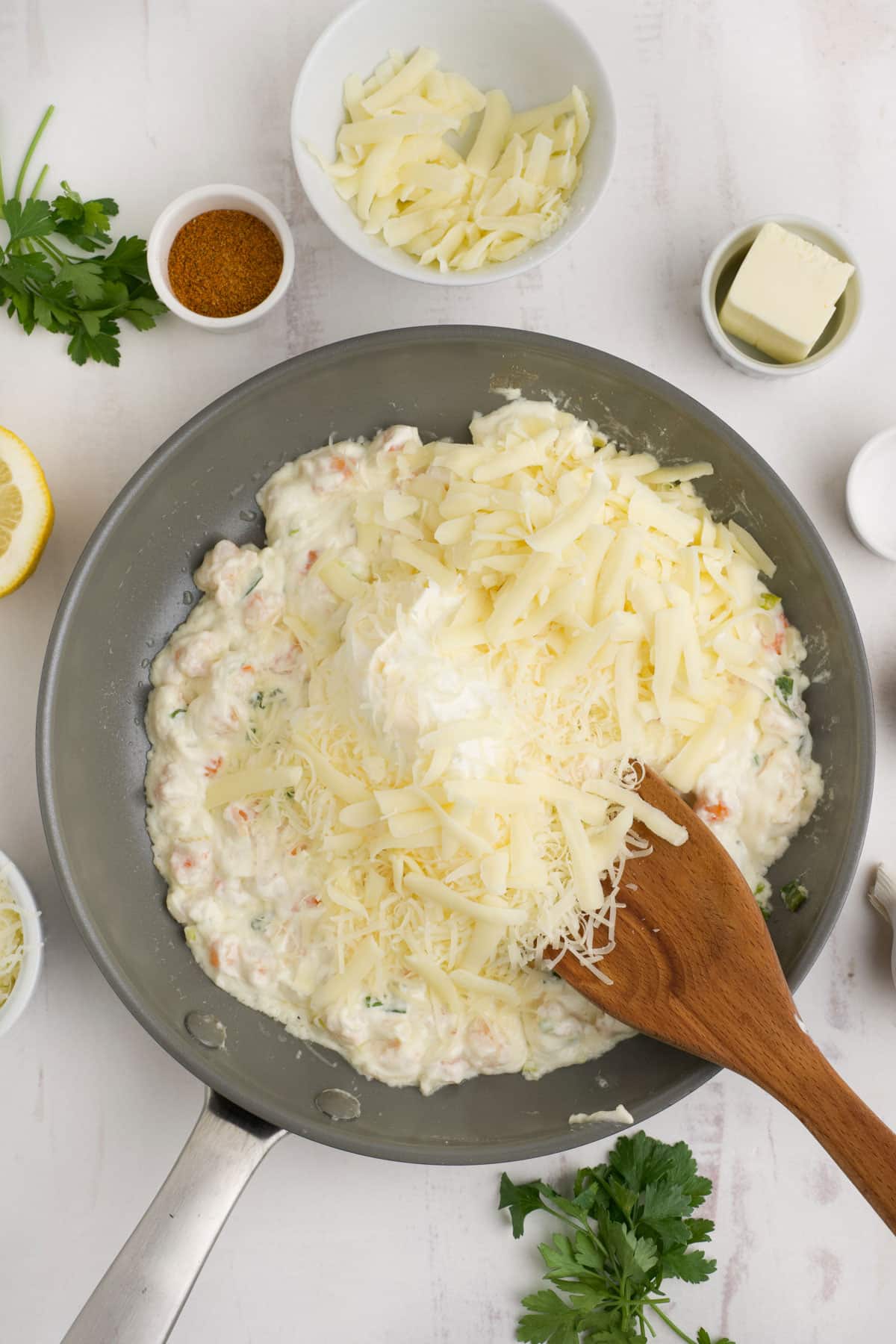 Shredded cheese is added on top of the shrimp and cream cheese mixture in the skillet.