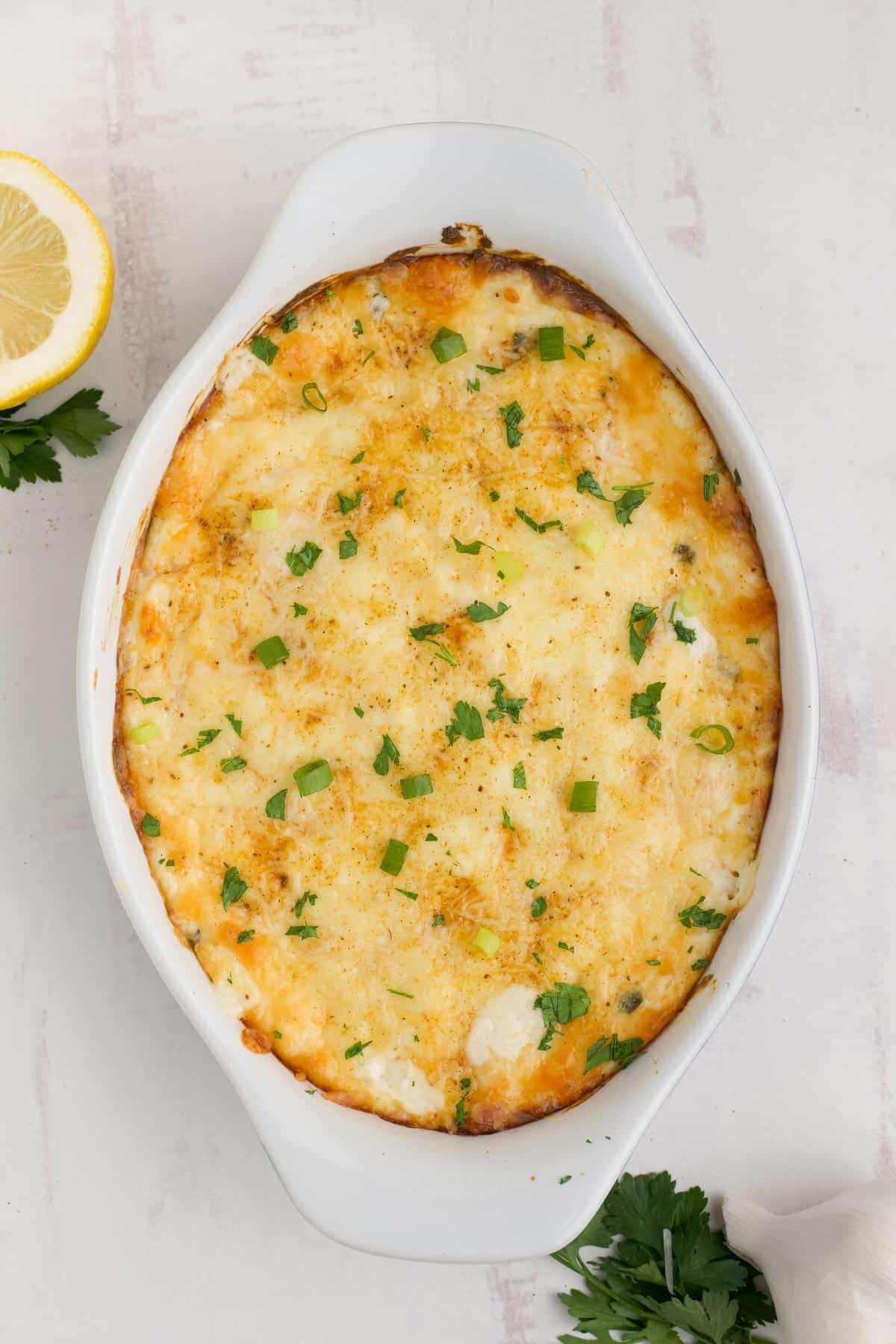 Hot shrimp dip in casserole dish after baking is sprinkled with some parsley.