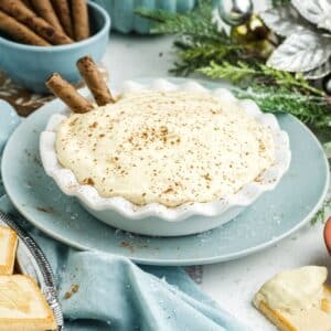 A bowl of eggnog dip on the table with a two pirouette cookies in it.