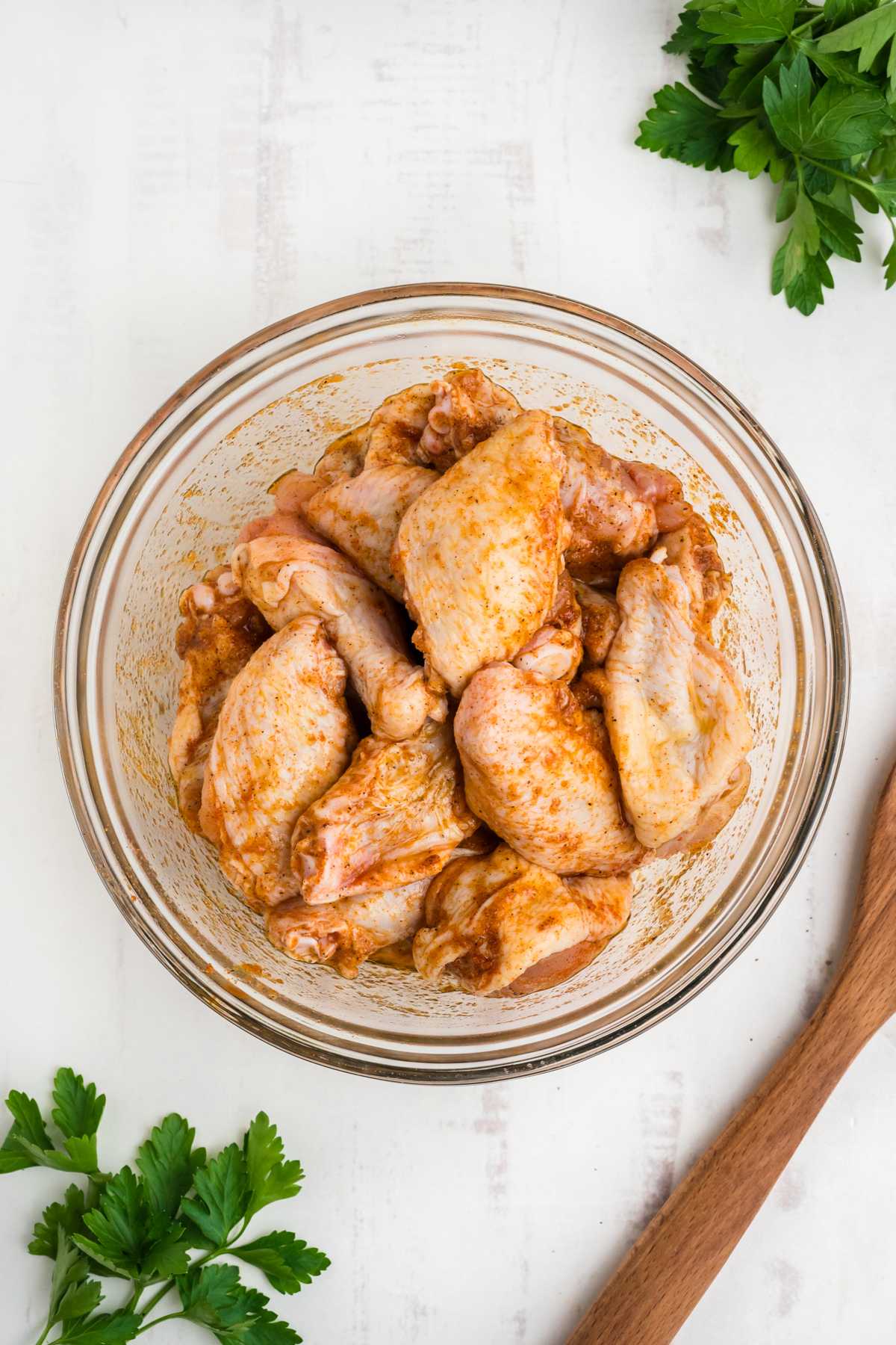 Wings in a bowl after tossed with spices.