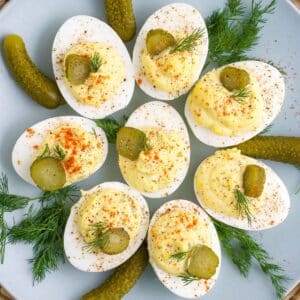 Dill pickle deviled eggs on a blue serving plate in a circle with one in the middle.