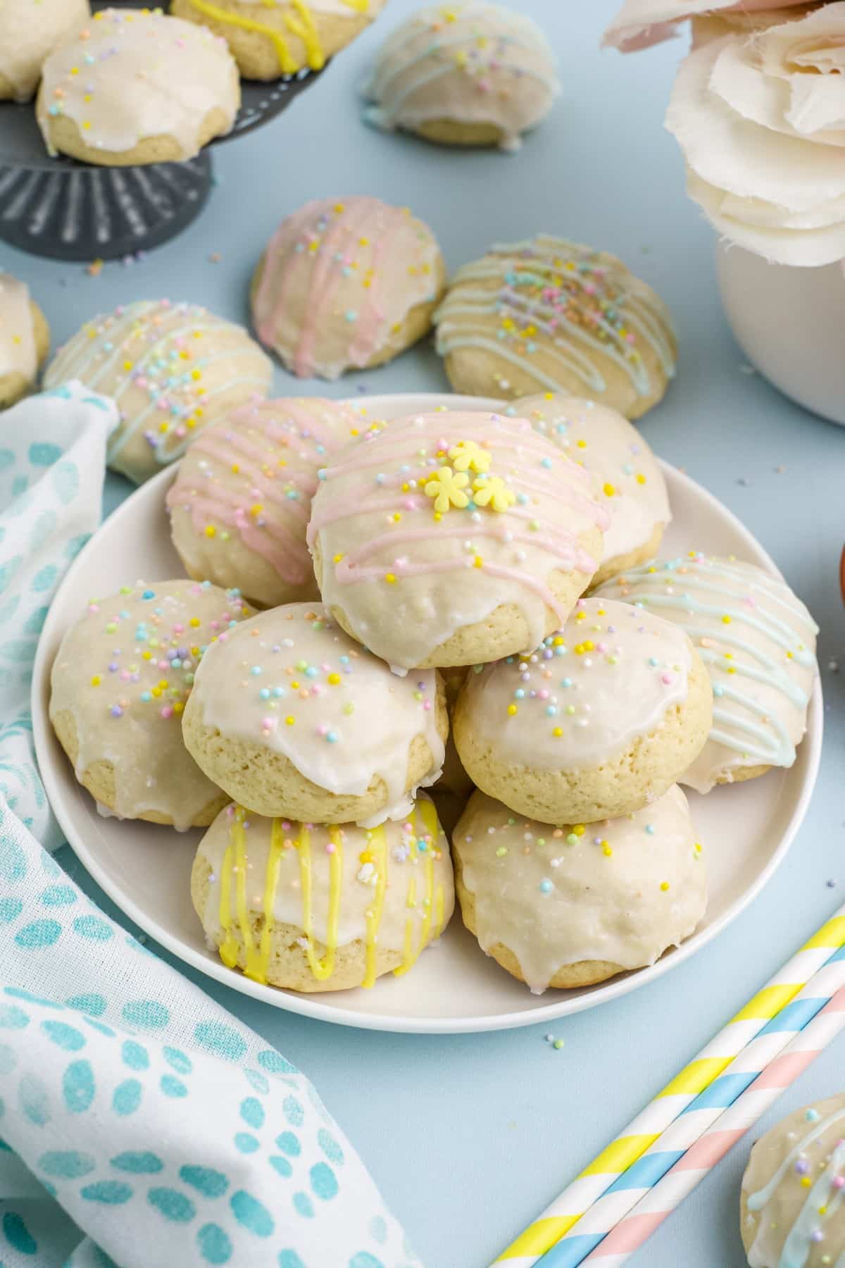 A plate of Italian Easter cookies on the table with pastel blue background and napkin to the side.