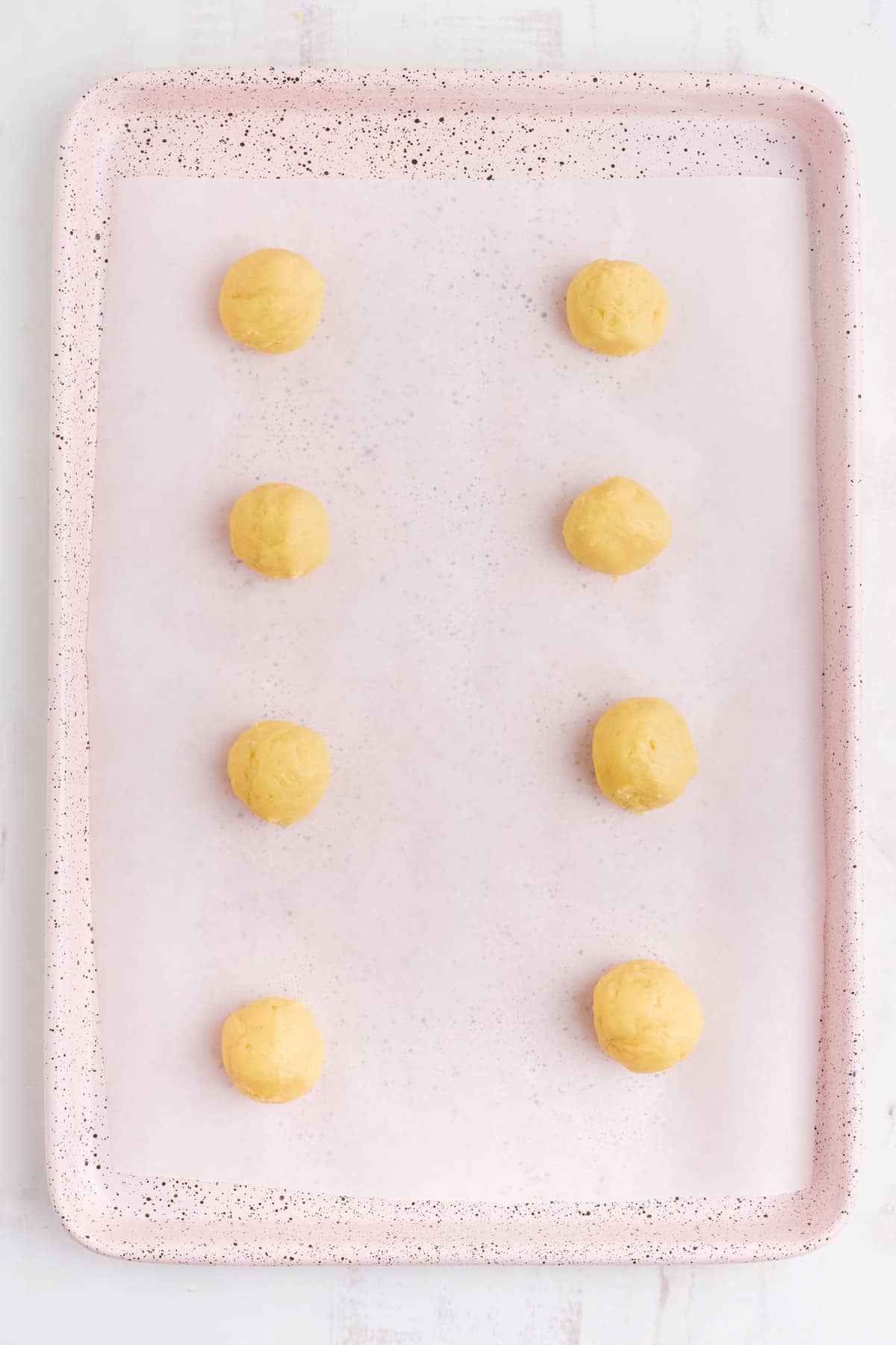 Cookie dough balls rolled and placed on baking pan.