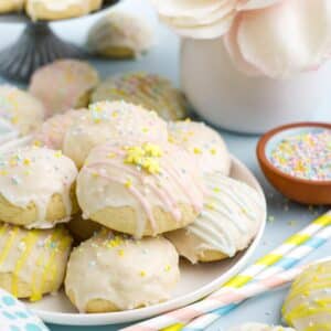 Pastel decorated Italian easter cookies on a plate on the table with sprinkles.