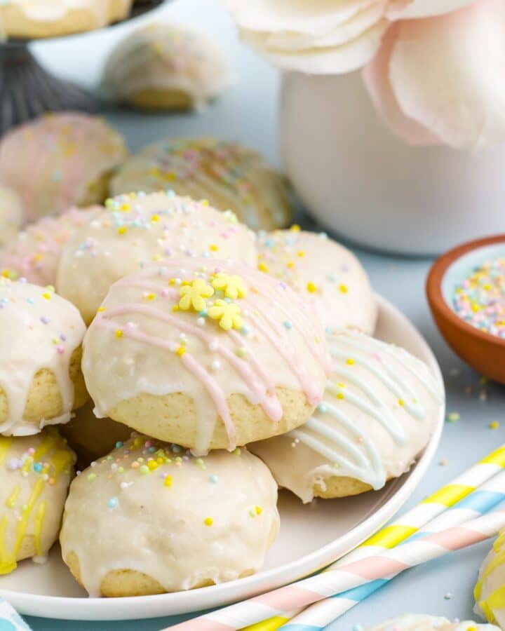 Pastel decorated Italian easter cookies on a plate on the table with sprinkles.