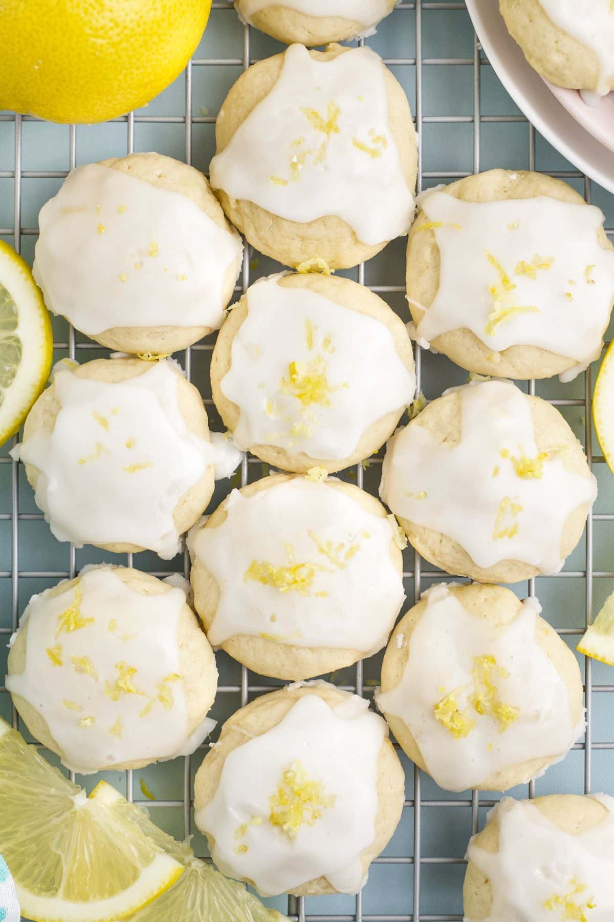 Lemon ricotta cookies lined up on a wire rack with glaze and zest on top.