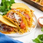 Spaghetti tacos on a plate topped with parmesan cheese.