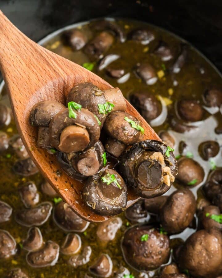 Slow cooker mushrooms with a spoon lifting out a portion.