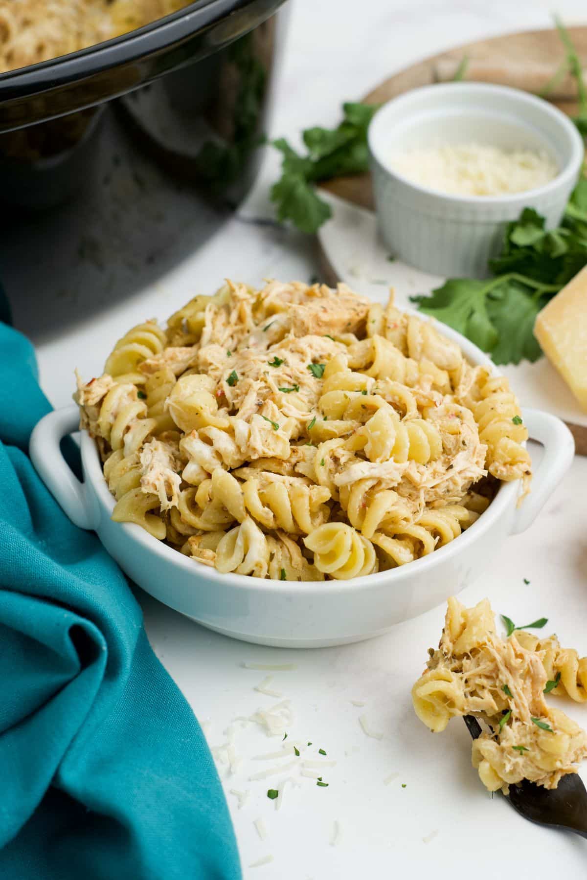 Crockpot garlic parmesan chicken in a bowl with a spoonful resting to the side.