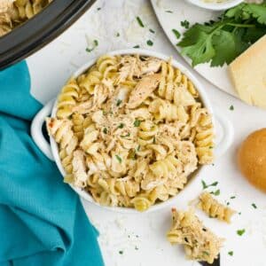 Crockpot garlic parmesan chicken pasta in a bowl on the table with more in the slow cooker.
