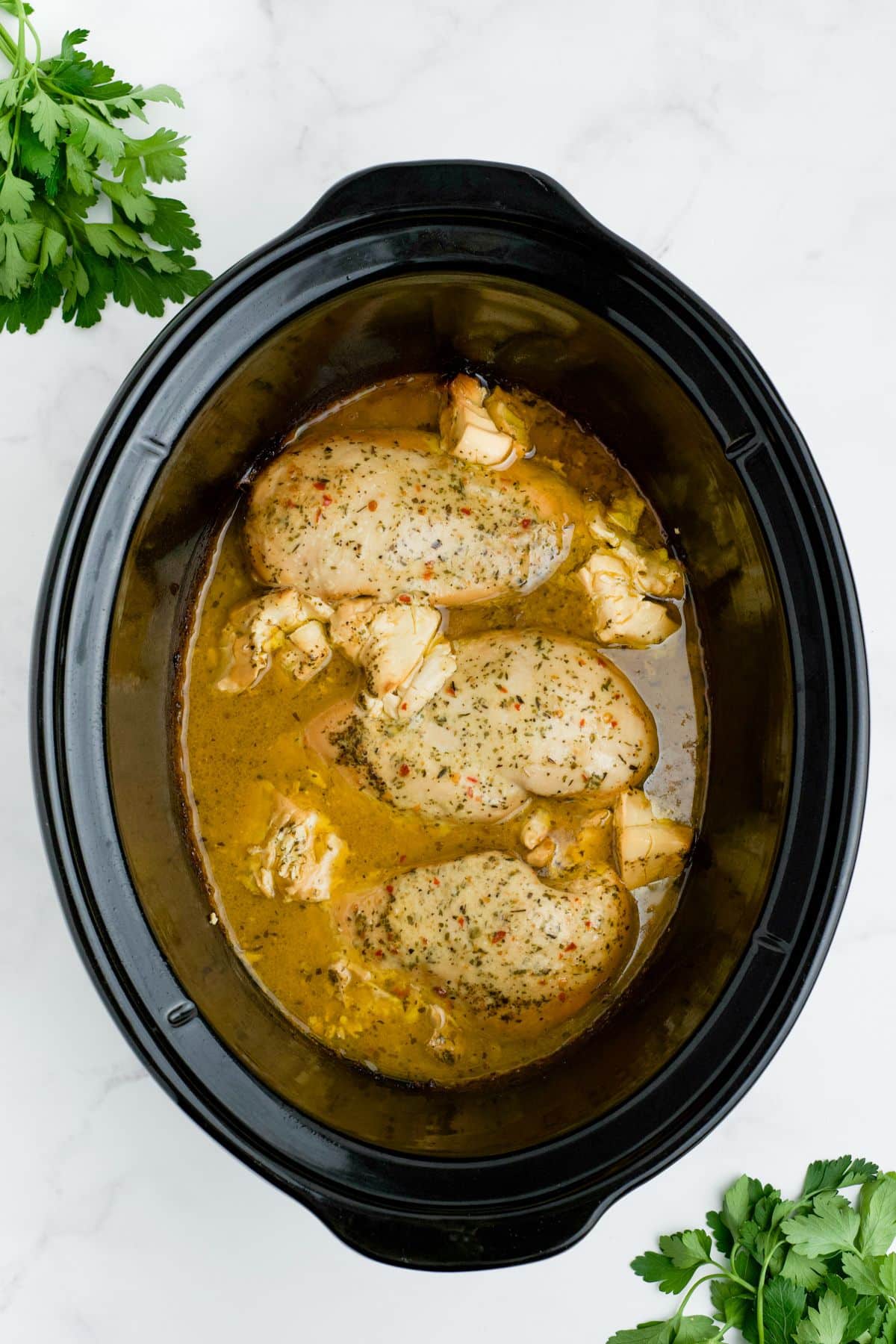 Cooked chicken in juices in the slow cooker.