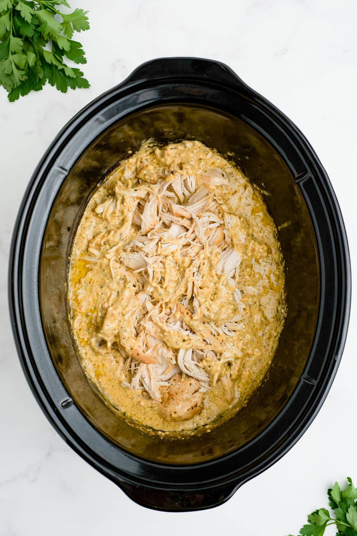 Chicken added to the sauce in a slow cooker.