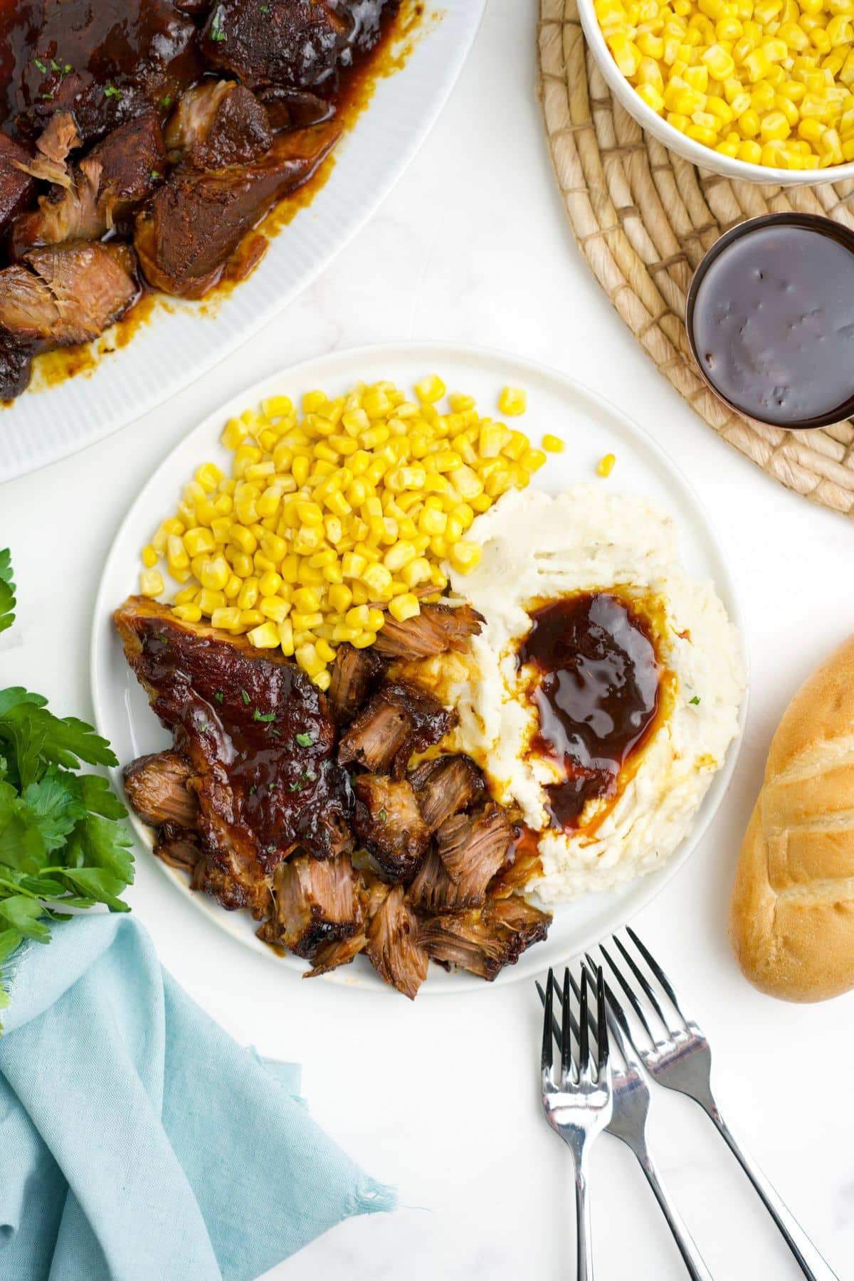 Boneless pork ribs served up on a plate with mashed potatoes and corn.