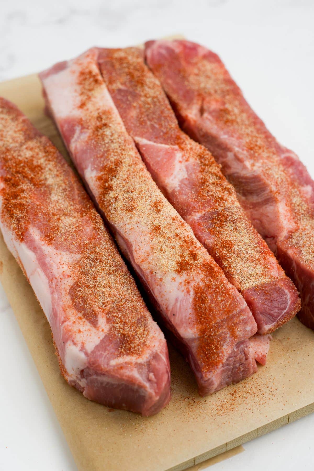 Ribs on a cutting board sprinkled with seasonings.
