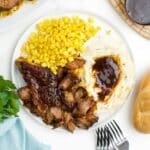 A plate of slow cooker boneless pork ribs on the table with mashed potatoes and corn.