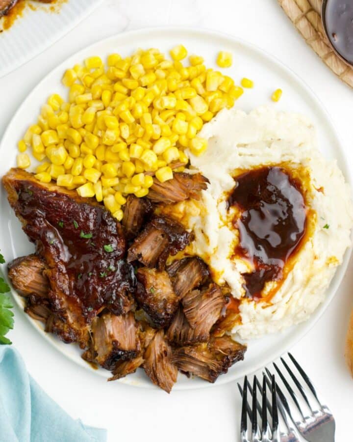 A plate of slow cooker boneless pork ribs on the table with mashed potatoes and corn.
