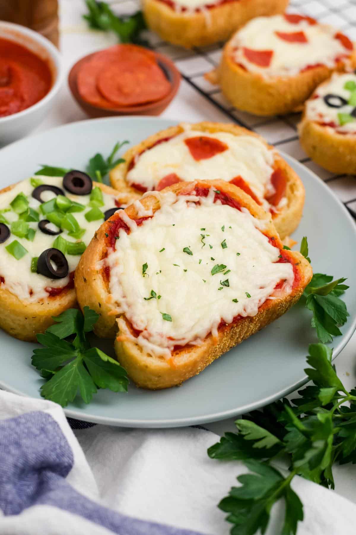 A gray plate topped with three different flavors of Texas toast pizza.