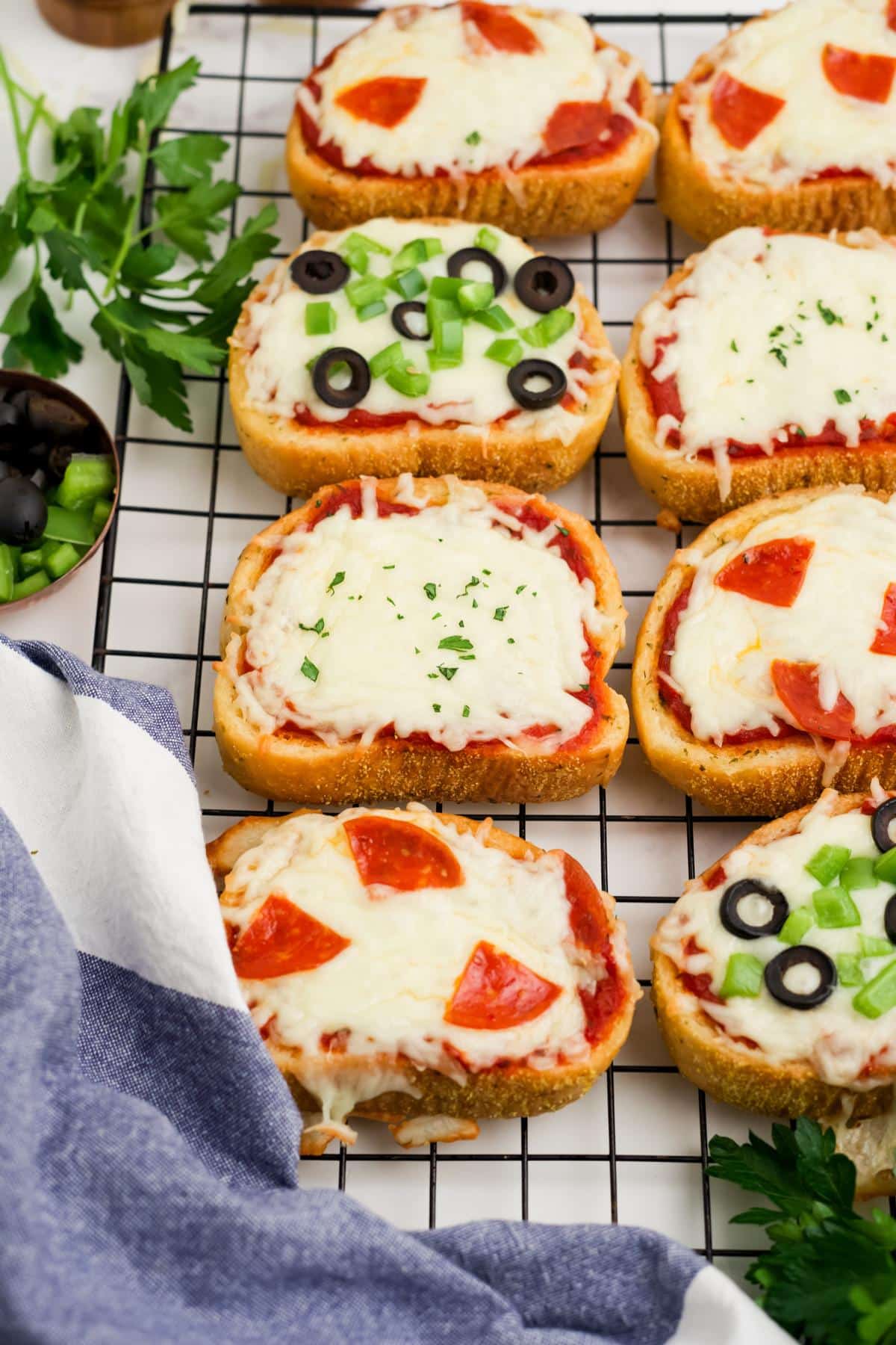 Pizzas on Texas toast on a wire rack on a table.