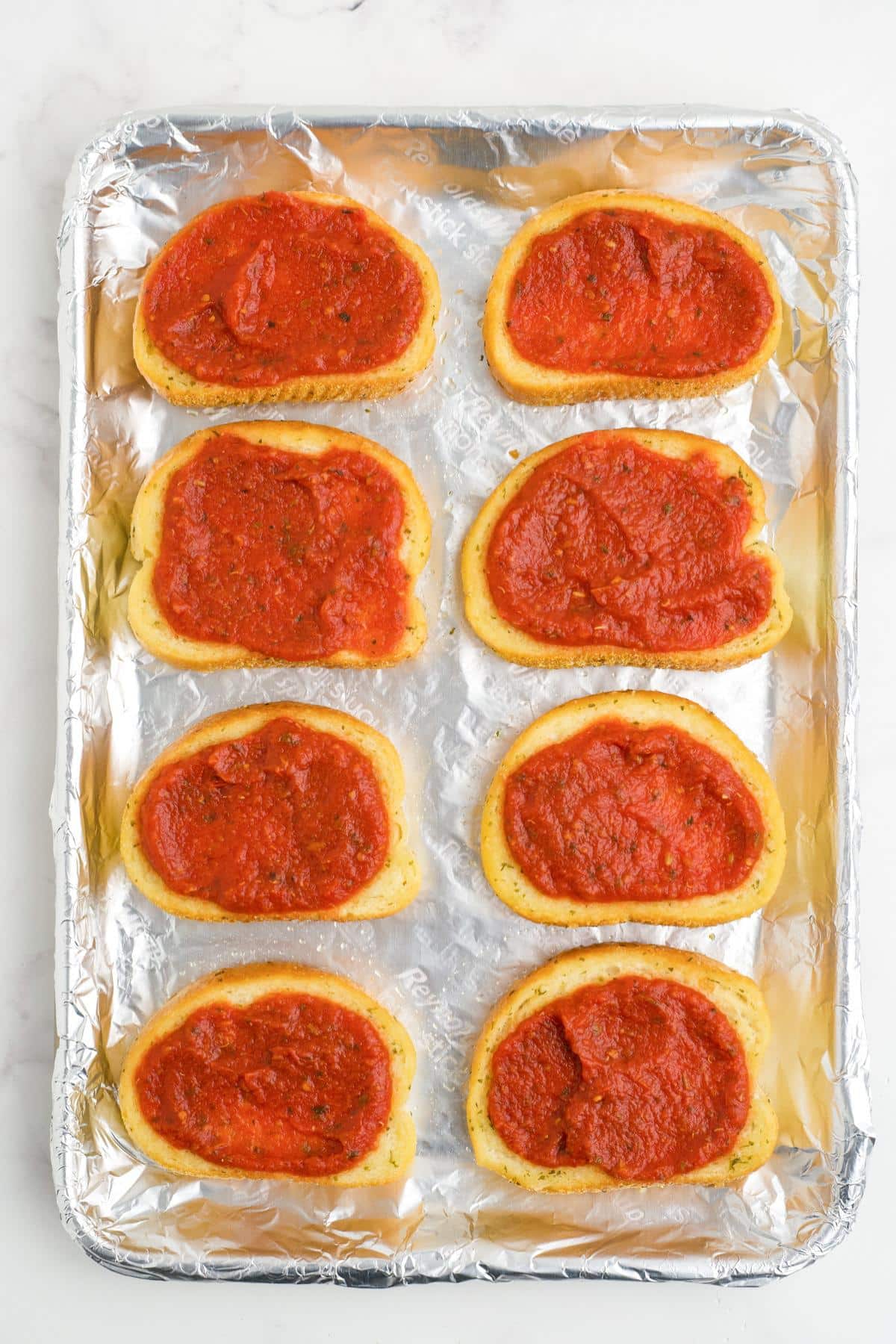 Pizza sauce spread on top of each piece of bread.