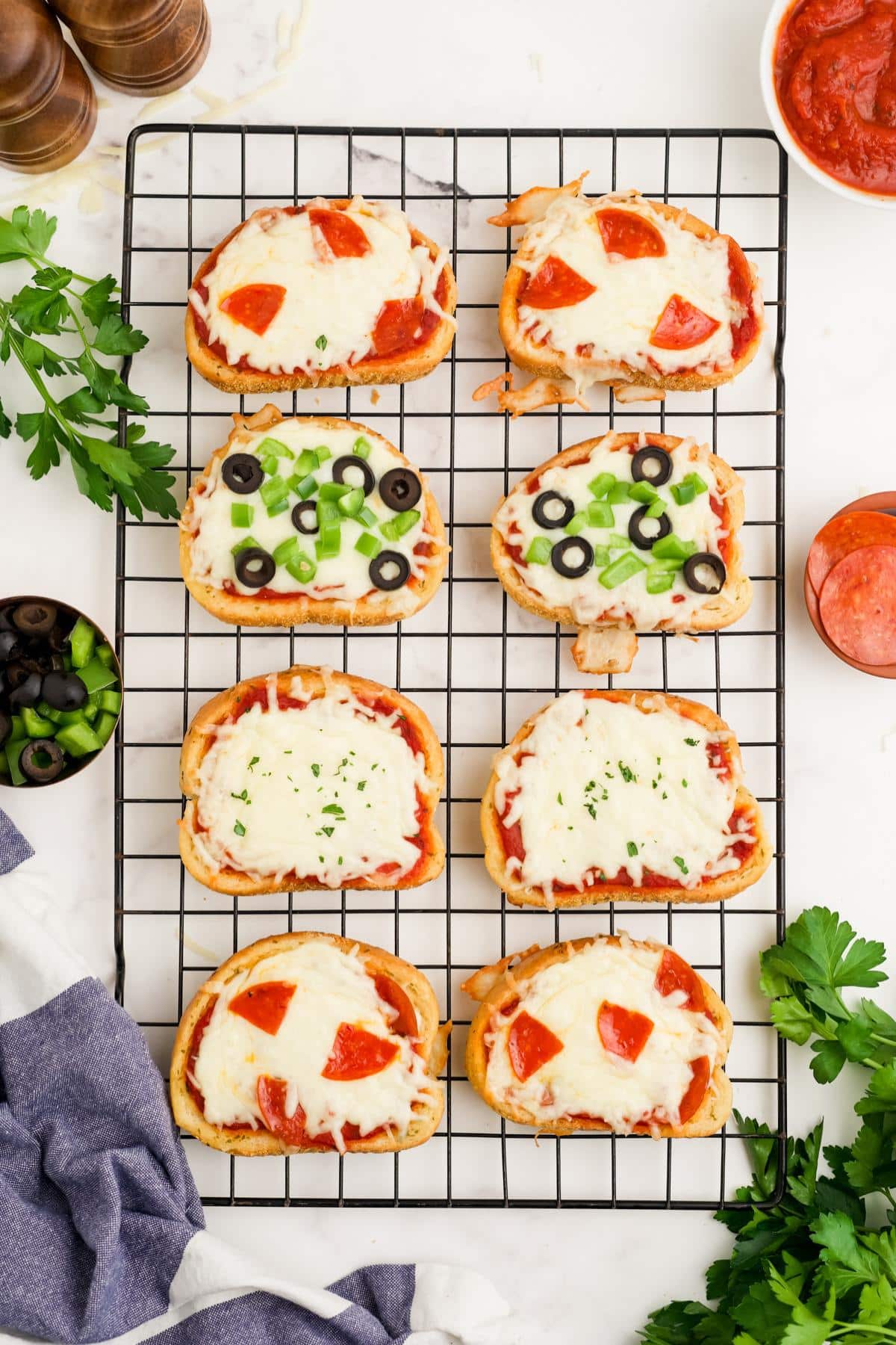 Texas toast pizzas with different toppings on a wire rack after baking.