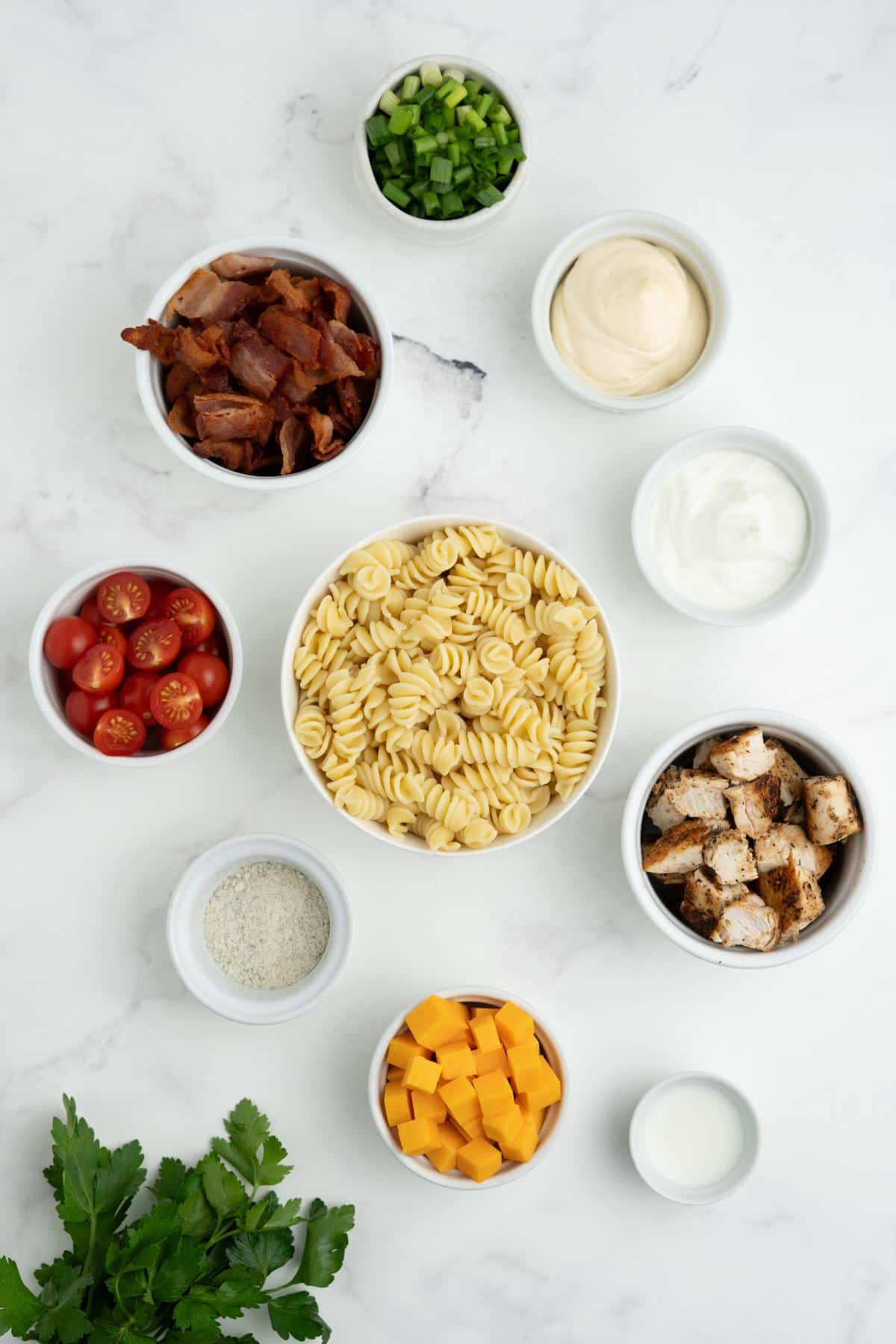 Ingredients to make bacon ranch pasta salad on the table.