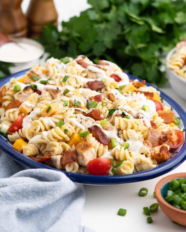 Chicken bacon ranch pasta salad served up on an oval plate garnished with parsley.